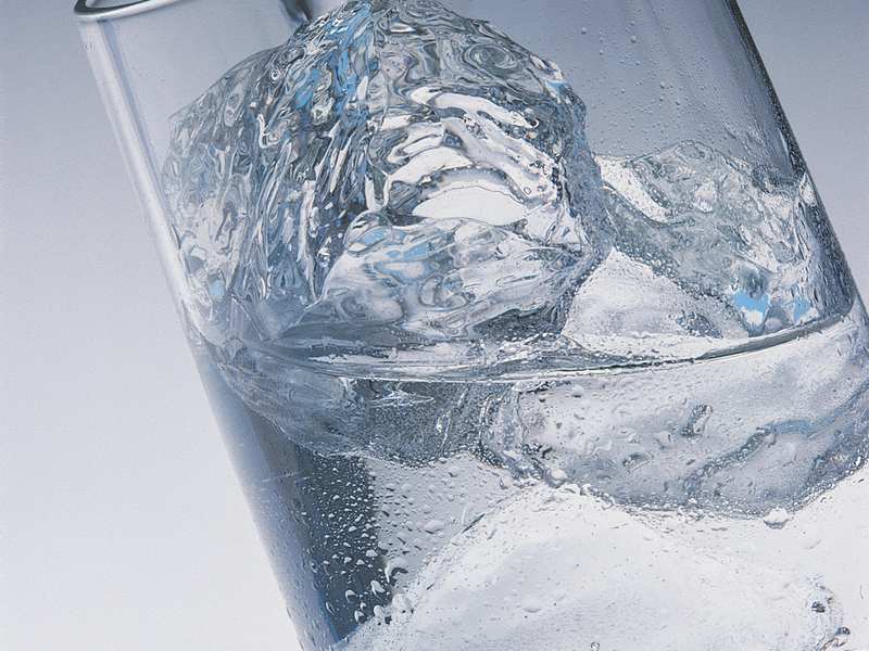 Fresh, clear water pouring into a glass over ice