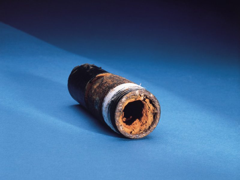 Cross-section of a water pipe badly corroded and choked with orange rust