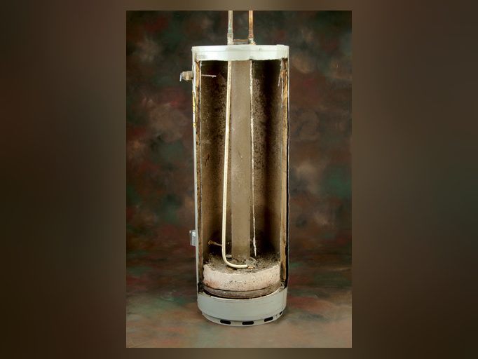 Cutaway of a water heater with its element buried in dark mineral scale