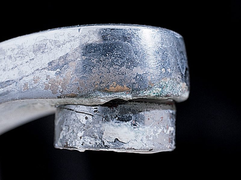 A chrome tap crusted with white limescale left by hard water